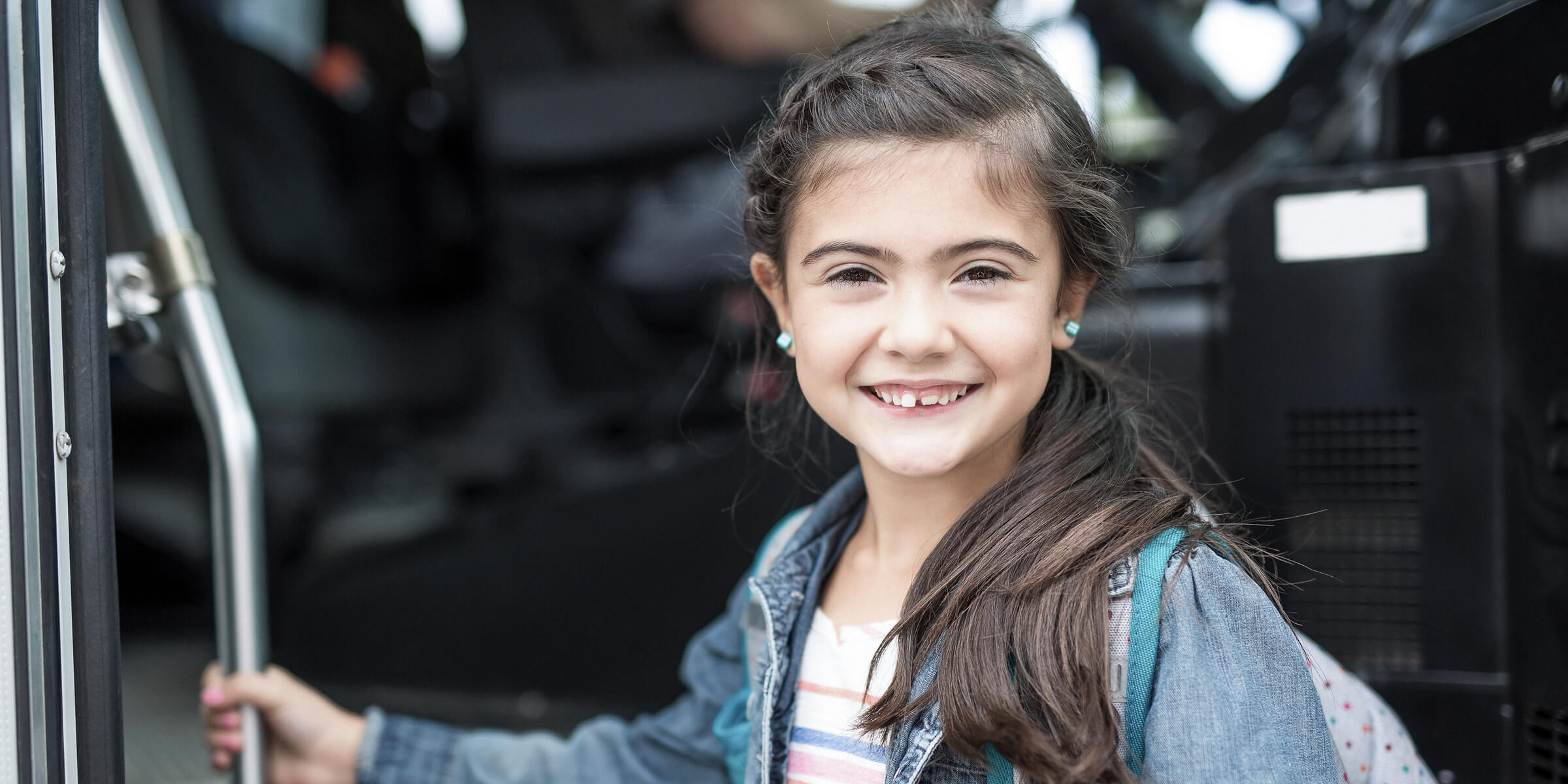 Bild zeigt lächelndes Mädchen im Buseinstieg