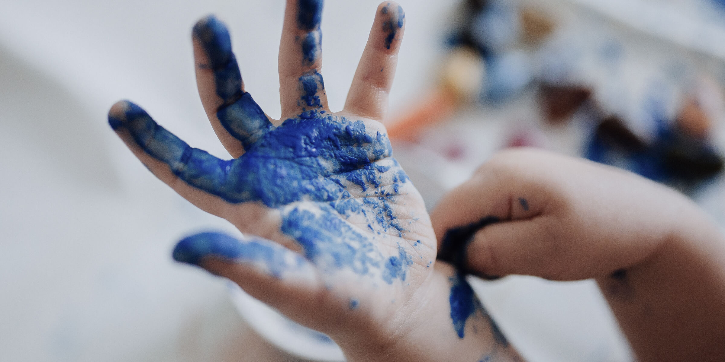 Bild zeigt eine blau angemalte Kinderhand