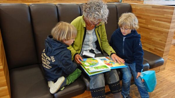 Ältere Frau liest zwei Kinder vor.
