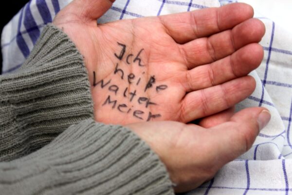 Die Hände eines Demenzerkrankten mit der Aufrischt "Ich heiße Walter Meier".