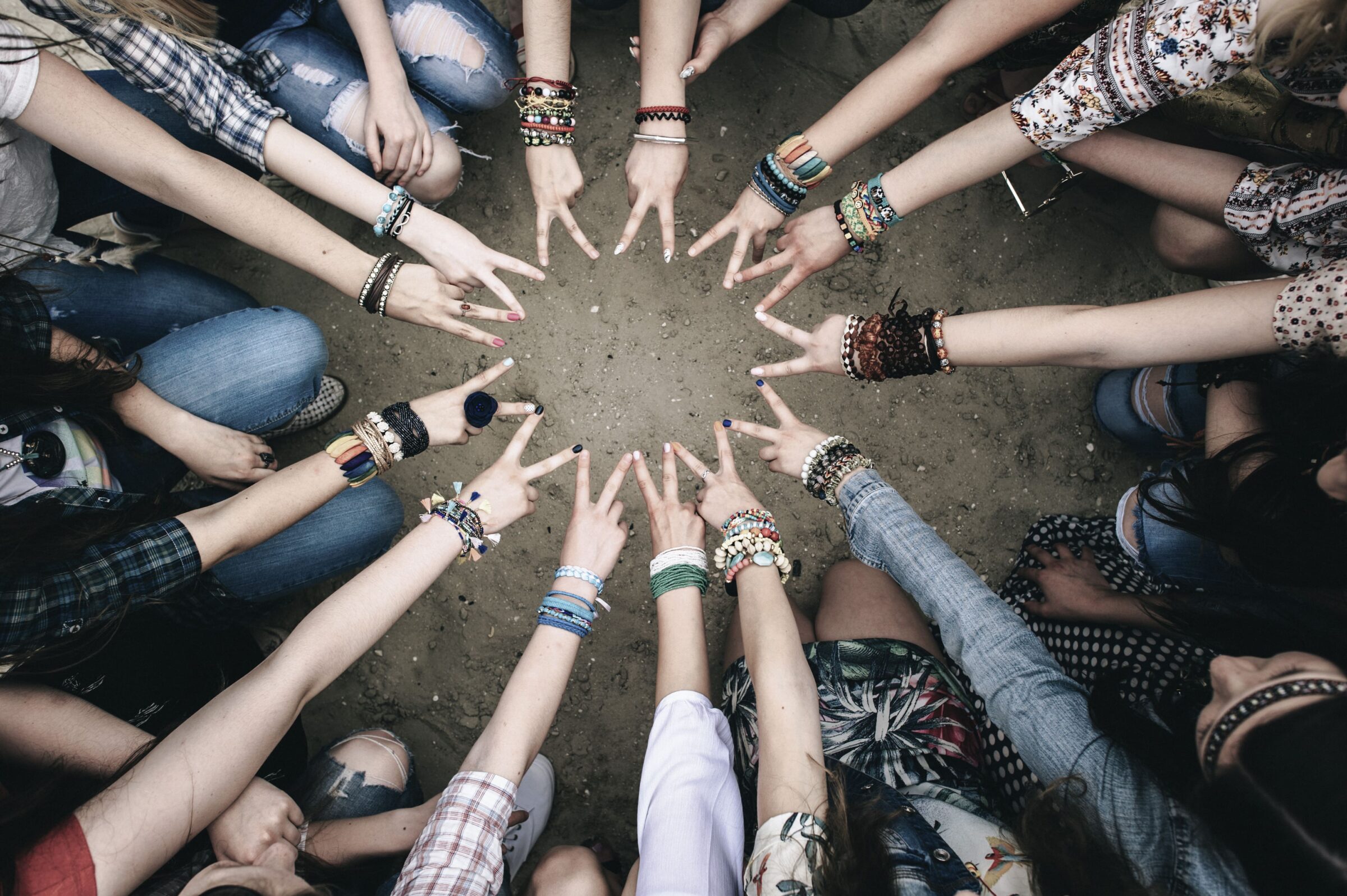 Jugendliche halten Ihre Hände im Kreis und machen das Peacezeichen.
