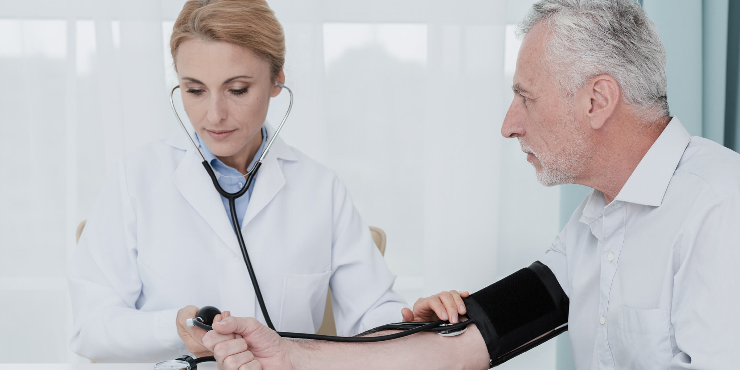Bild zeigt eine Ärztin, die den Blutdruck eines Patienten misst